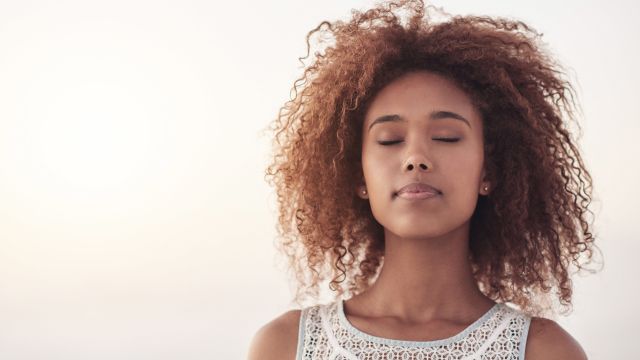 Woman with her eyes closed and meditating to stop a panic attack 