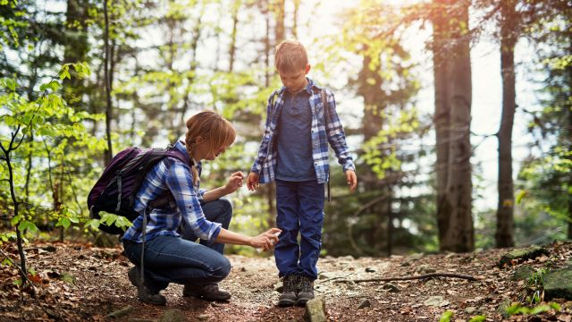 woman spraying tick repellant on her son