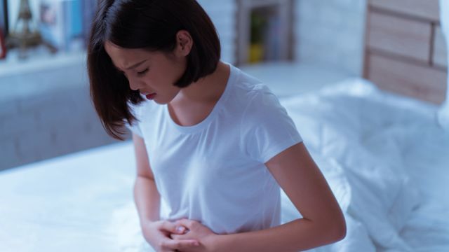 Young woman holding her hands over her stomach