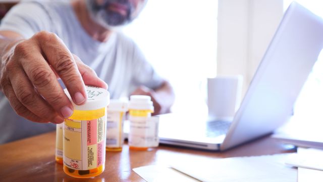 Man sitting at dining room table and reaching for prescription medications