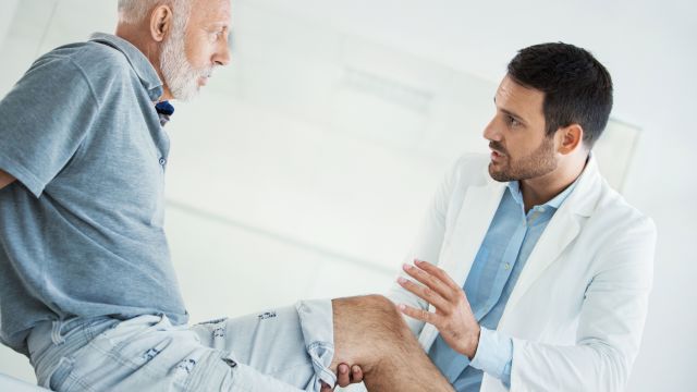 Senior man having knees examined by doctor