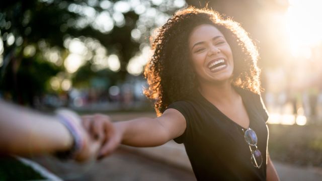 A smiling woman holds the hand of her partner, feeling both physical and mental attraction. 