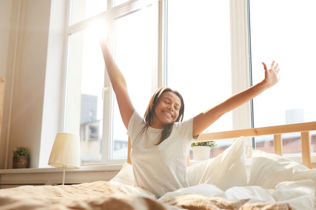 Young woman raised arms morning wakeup