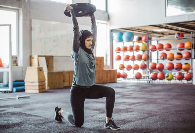 Hijab-wearing woman in gym lifting weight