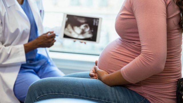 Someone with a clipboard takes notes while two other people speak to them about preeclampsia. 