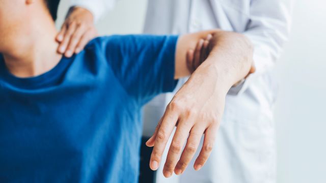 A doctor performs a physical exam for joint pain on a young man.