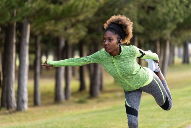 A young woman in running clothes stretches her legs. Exercise can help protect your joints from the damage of psoriatic arthritis.