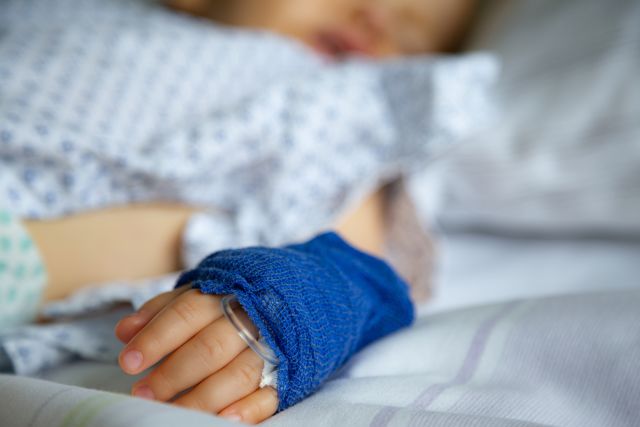 child with IV sleeping in hospital bed 