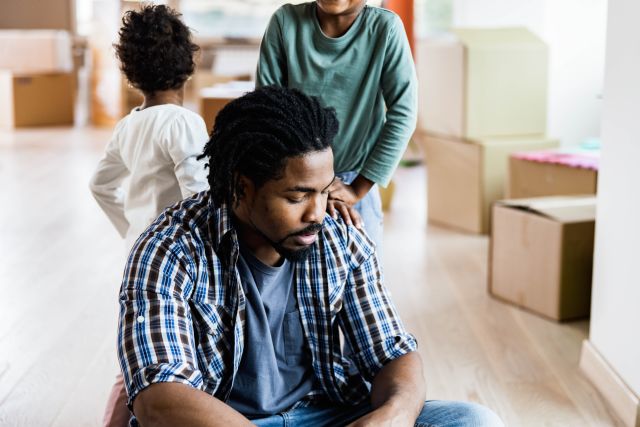 Anxious Black man sitting with children