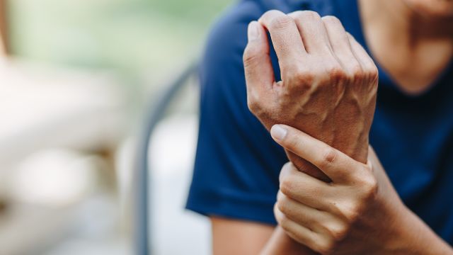 A man with psoriatic disease rubs his wrist. He has psoriasis and joint pain and wonders: Can psoriasis cause arthritis? 