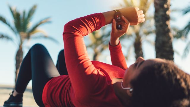 A woman with psoriatic arthritis and high blood pressure rests after a workout—checking her heart rate on a smartwatch. 