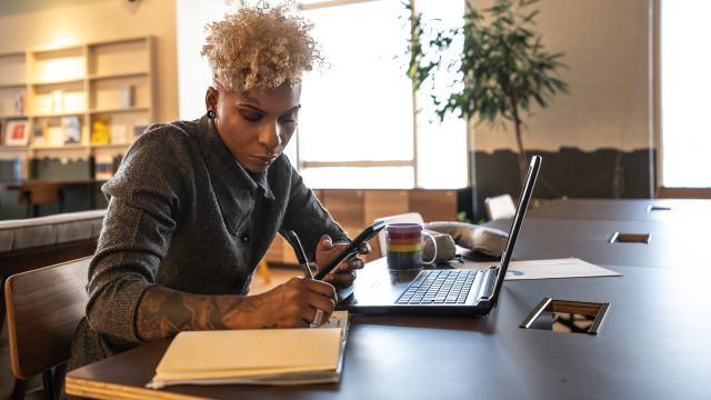 Adult businesswoman doing work on a laptop in a coworking space.