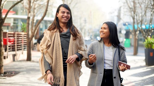 Two young friends having a discussion while walking through the city.