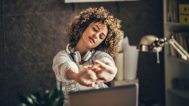 Young woman stretching at desk.