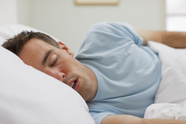 man sleeping in bed with mouth open, snoring