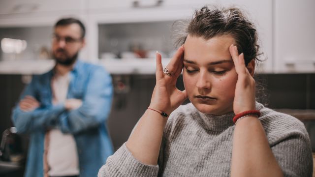 Woman massaging her temples while arguing with her partner.