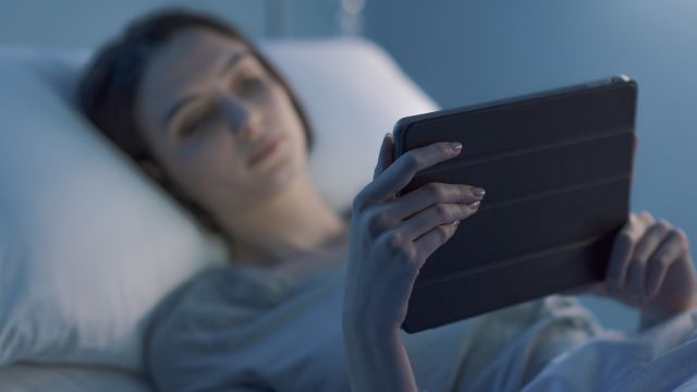 Woman recovering from surgery, holding a tablet.