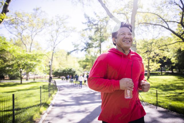 Smiling Latino man jogs in a city park.