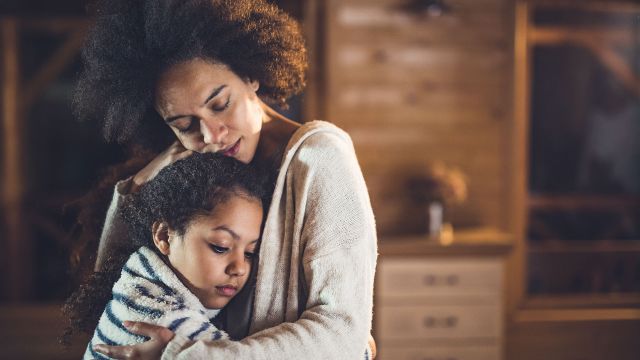 Cancer caregiver offering support and hugging a young girl.