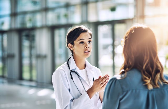 A young female doctor speaks with a female patient.