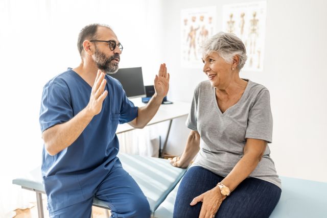 A middle aged male doctor speaks with an elderly woman on her knee replacement surgery