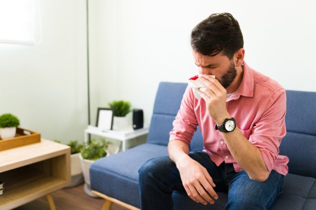 person on a couch experiencing a nosebleed