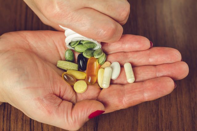 person pouring colorful pills out of a bottle into one hand