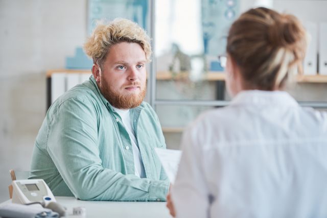 Young man with obesity listening to a healthcare provider.