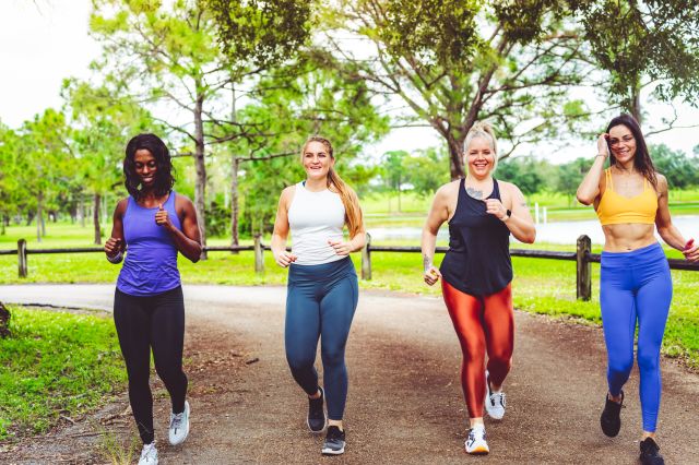 a group of four female friends of different body types are walking for exercise in the park