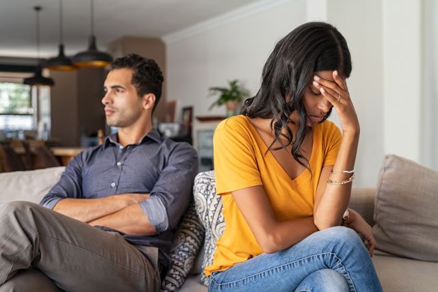 a young couple heterosexual with relationship issues sit on a coach looking away from each other