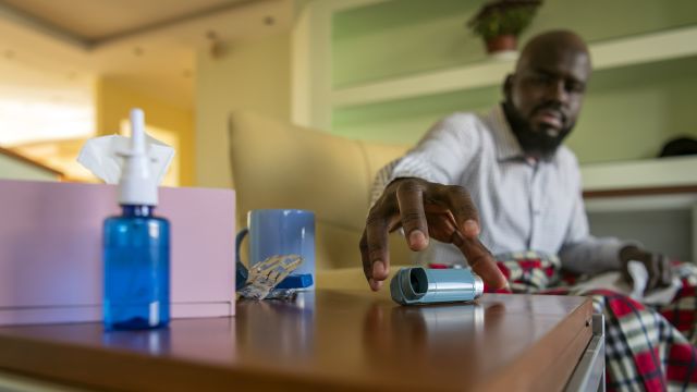 An older man reaches for a bronchodilator. Pneumonitis is a potential side effect of lung cancer and can make it difficult to breathe.