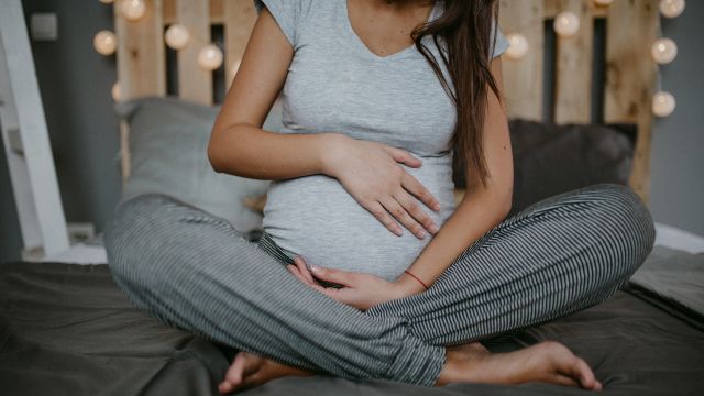 A pregnant woman relaxes on a bed. Certain psoriasis medications may need to be avoided during pregnancy.