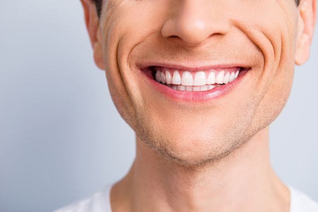 close up of a young White man's smiling mouth, filled with white teeth
