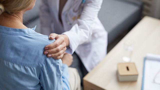 A healthcare provider comforts a patient who is having a difficult time talking about embarrassing skin disorder symptoms.