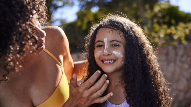 Mother applies sunscreen to her young child.
