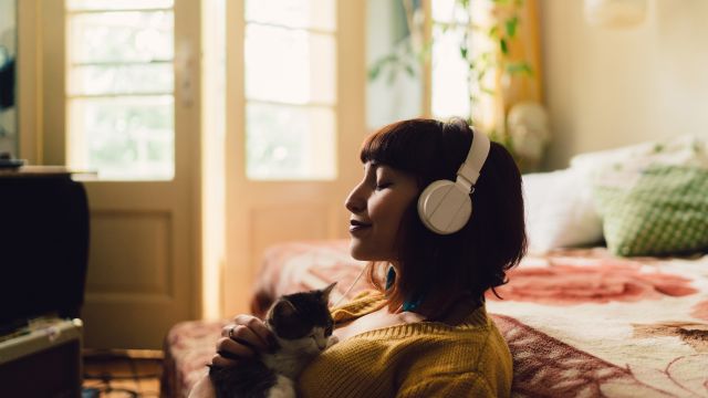A woman relaxes by listening to music and spending time with a kitten. Psoriasis patients are advised to find ways to de-stress.