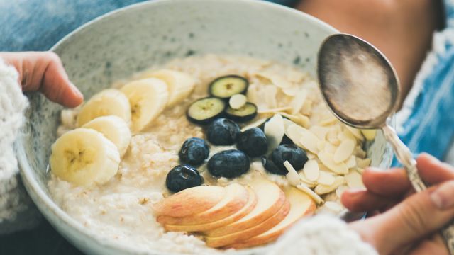 A young woman with a bowl of oatmeal. Carbohydrates are an important part of a nutritious diet for people with porphyria.