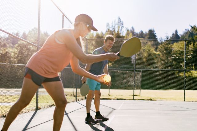 Two young people smiling and enjoying themselves while playing pickleball