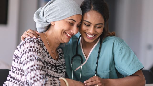 Nurse hugging a smiling cancer patient