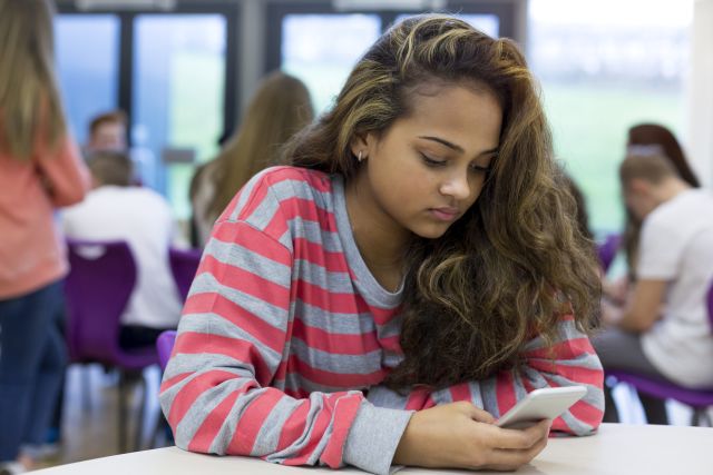 high school student using phone looking stressed