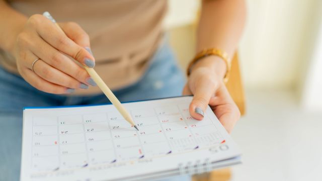 Woman plans out her month on a calendar.
