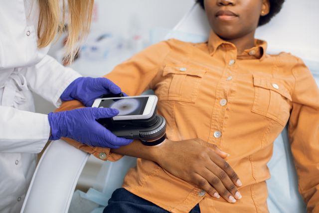 a young Black woman receives a skin exam from a dermatologist