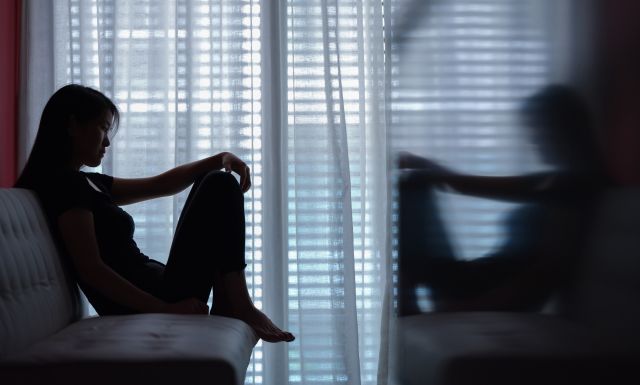 Woman with bipolar disorder sitting alone in a dark room