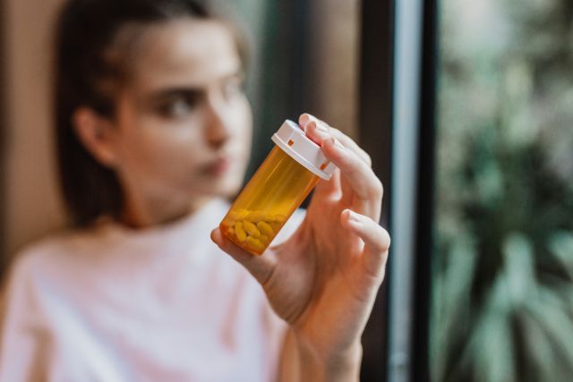 Woman holds her bottle of antidepressants for bipolar disorder 