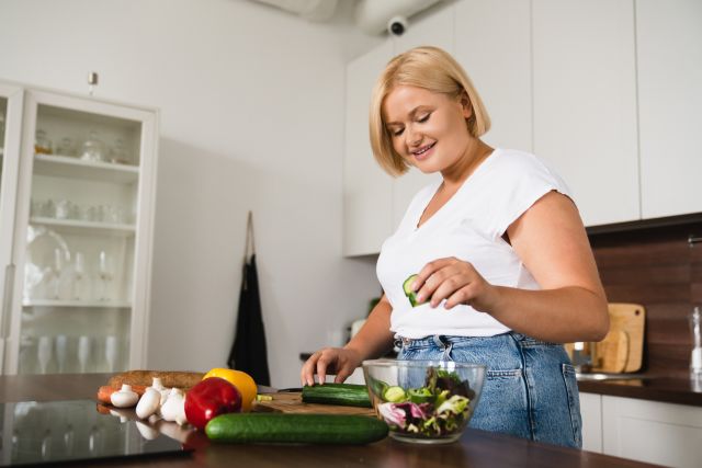 an overweight woman makes a health meal in her kitchen