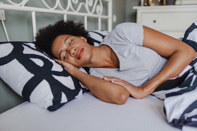 African-American woman with joint pain sleeping in bed at home 