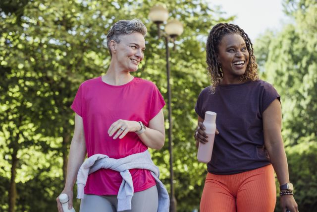 a middle aged Black woman and a middle aged white woman enjoy each other's company as they set out for a walk in the park