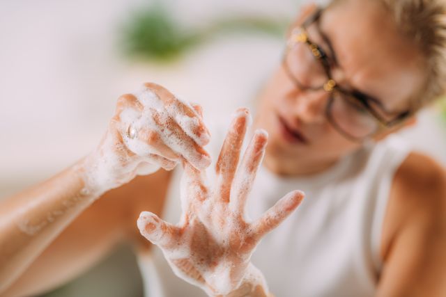 A blonde white woman with obsessive compulsive disorder scrubs her hands with soap