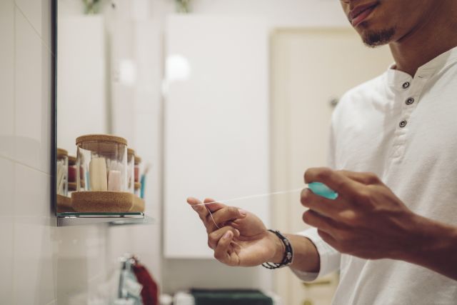 Closeup of man pulling floss out of dispenser