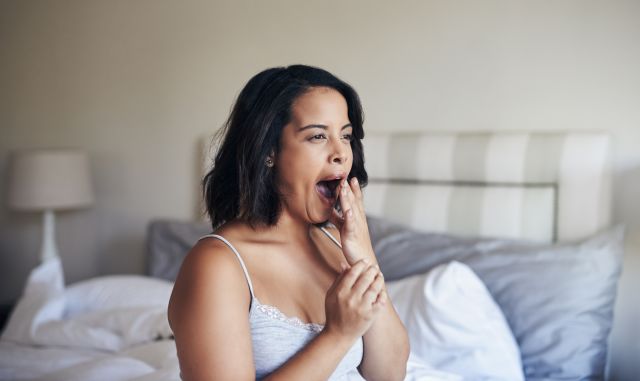 Woman sitting up in bed after waking, yawning